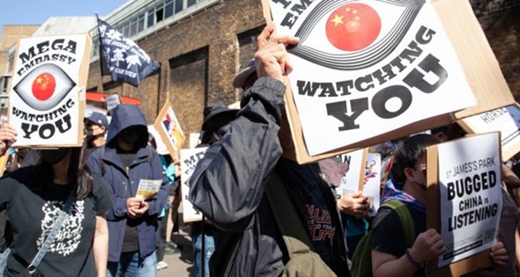 Protesters with signs saying Mega Embassy Watching You