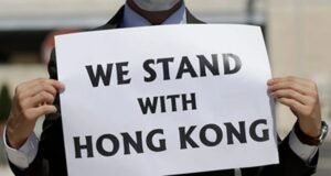 Man holding sign saying We Stand With Hong Kong
